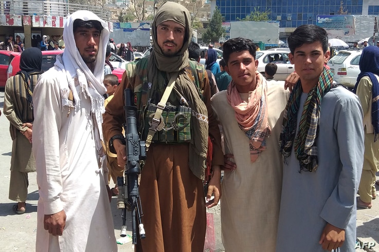 A Taliban fighter (2L) is seen with locals at Pul-e-Khumri on August 11, 2021 after Taliban captured Pul-e-Khumri, the capital…