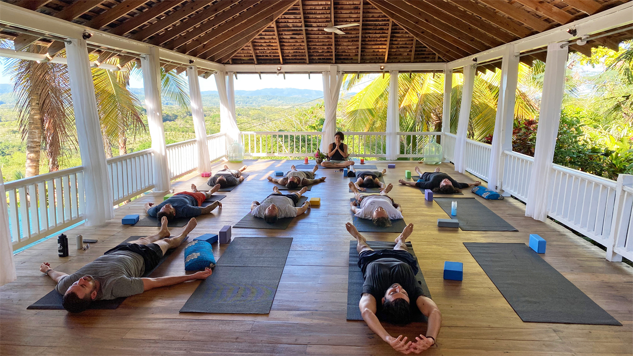 A photo of people practicing yoga on mats inside of a gazebo.