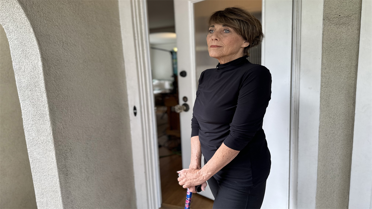 A photo of a woman posing for a portrait, propping herself up with a cane.