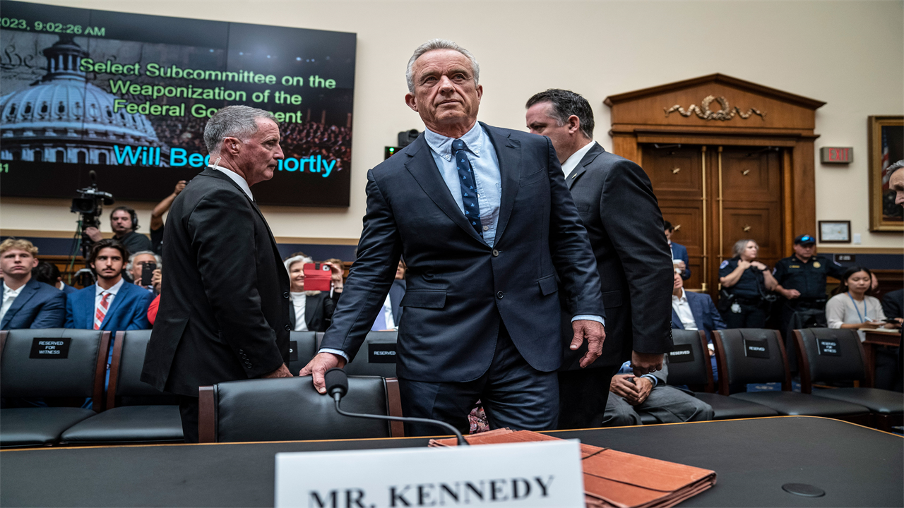 A photo of Robert F. Kennedy taking a seat during a House subcommittee hearing.