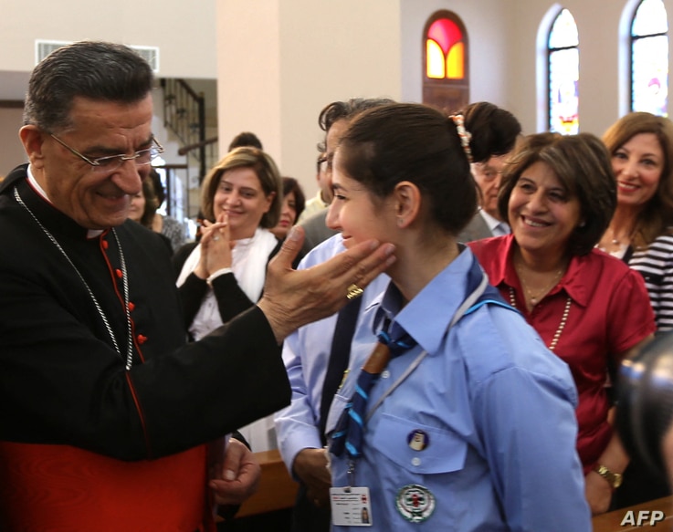 The Maronite Patriarch of Antioch and Cardinal of the Catholic Church, Mar Beshara Boutros Rai (L) blesses a girl scout as he…
