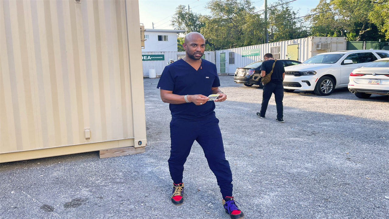 A photo a man in scrubs standing outside.