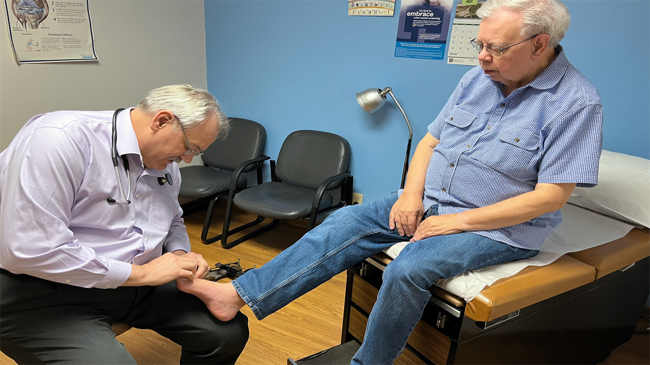 A photo of a doctor examining a male patient's foot.