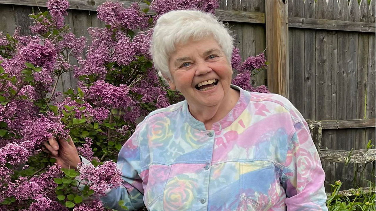 A photo of an older woman smiling outside.