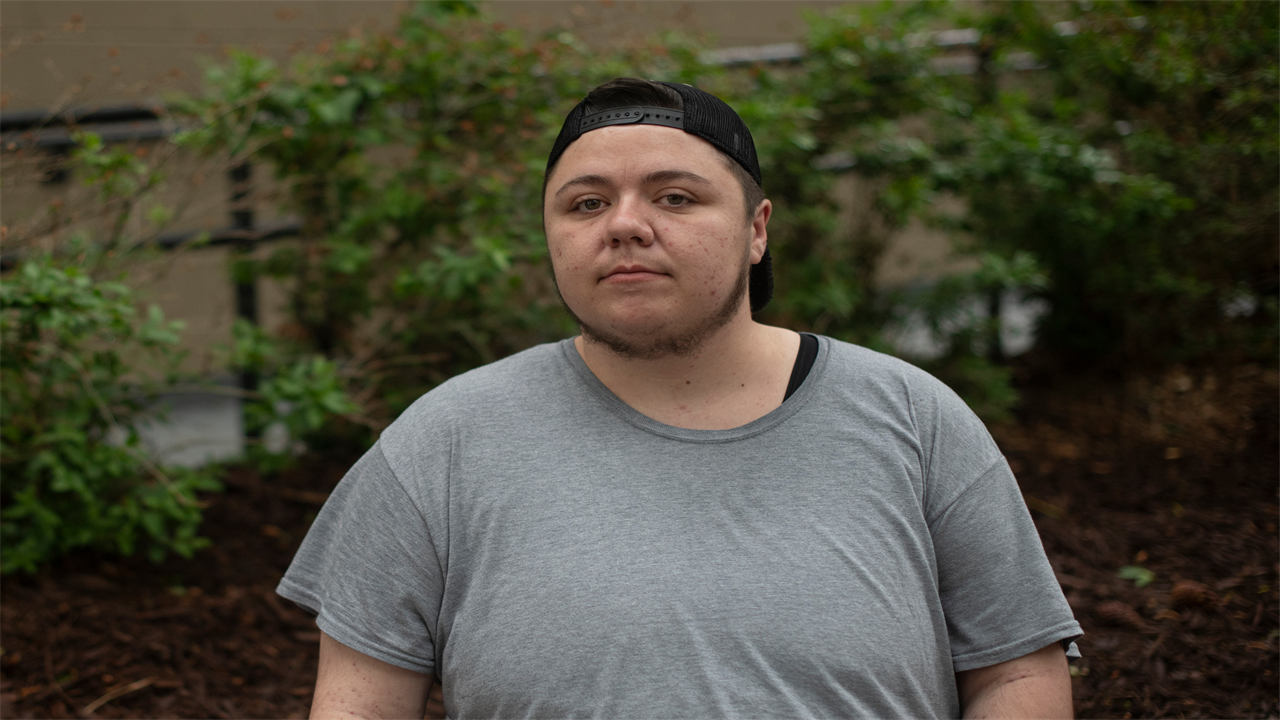 A photo of a man posing for a portrait outside.