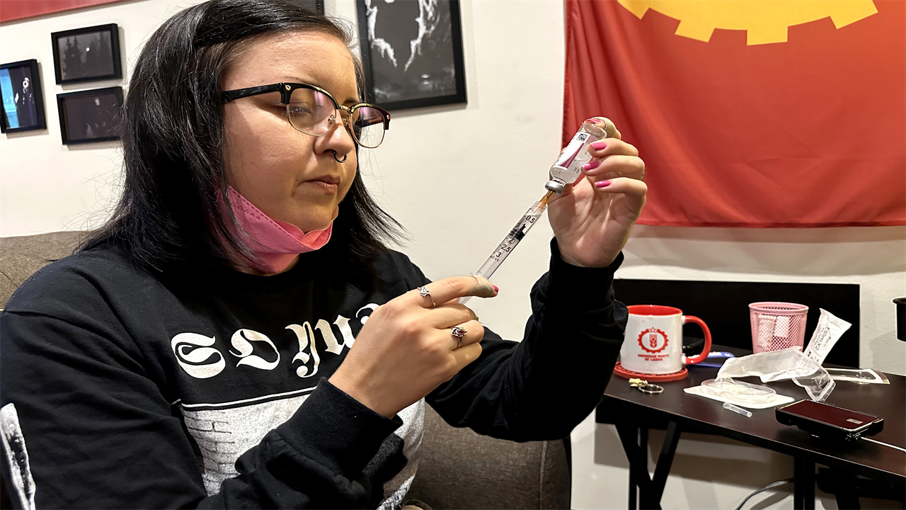 June Voros is preparing insulin by drawing fluid from a vial with a needle.