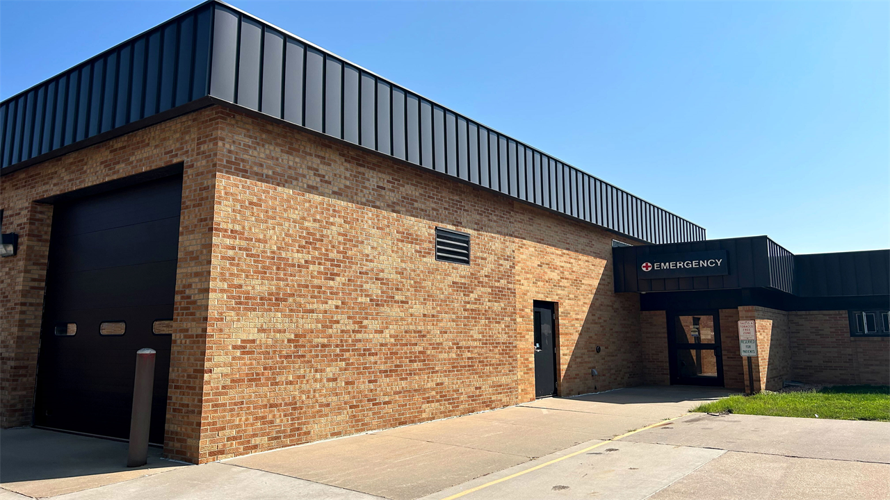 The exterior of a building. A sign above the door reads "Emergency".