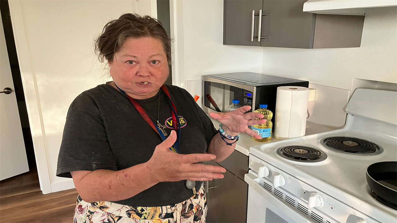 Carla Brown stands in the kitchen of her home and faces towards the camera.
